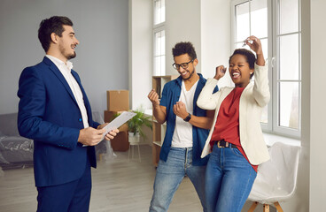 Overjoyed multiracial couple buyers celebrate deal buy first house from real estate agent. Broker or realtor give keys to new home to happy customers congratulate with ownership. Realty concept.