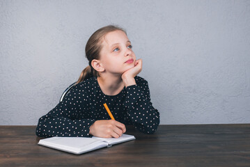 Wall Mural - A European girl is sitting at the table doing her homework. Studies. Homework.