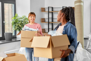 Wall Mural - moving, people and real estate concept - happy smiling women with boxes at new home