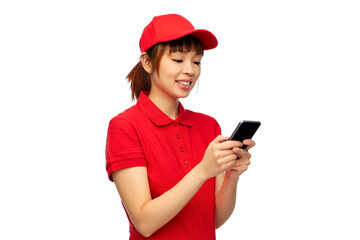 Wall Mural - profession, job and people concept - happy smiling delivery woman in red uniform with smartphone over white background