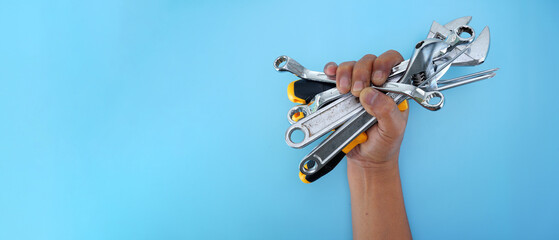 Wall Mural - hand holding  different types of black yellow hand tools isolated blue background