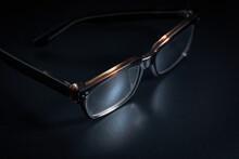 Dark Brown Frame Eyeglasses With Presbyopia Lenses On A Black Floor.