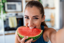 Young Woman Eats A Slice Of Watermelon In The Kitchen. Portrait Of Young Woman Enjoying A Watermelon.