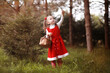 A little girl in a red hat and dresses is walking in the park. Cosplay for the fairytale hero 
