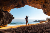 Fototapeta Zwierzęta - A woman on vacation at the beach cave in the Algarve, Praia da Coelha, Albufeira. Portugal