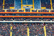 Viele Menschen verfolgen ein Fußballspiel auf der Tribüne eines Stadions in einer Teleaufnahme