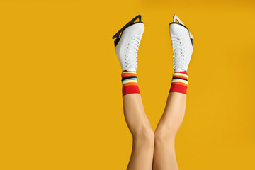 Wall Mural - Woman in elegant white ice skates on yellow background, closeup of legs. Space for text