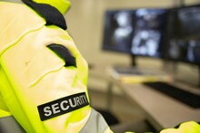 Security Officer With A Yellow Jacket Sitting At The Office In Front Of The Computer