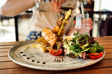 Women having her lunch or dinner, food close up. Salman with salad served on a big plate and a glass of water in hands