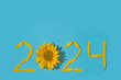 Sunflower petals in the form of numbers 2024 on a blue background. 2024 new year new reality. Summer it is time for traveling