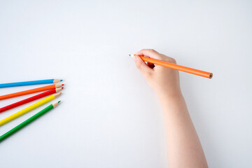 High angle shot of child hand draws a orange pencil