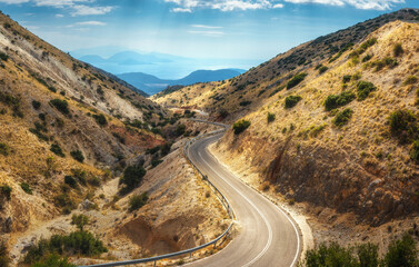 Wall Mural - aerial view of winding mountain road, blue sky with clouds at sunny day in summer. lefkada, greece. 