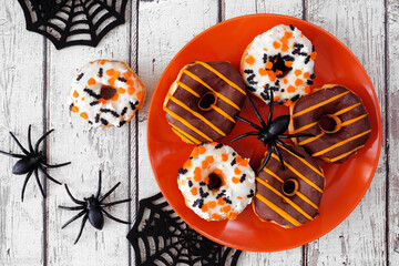Wall Mural - Spooky Halloween themed donuts. Overhead view table scene on a white wood background.