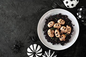 Poster - Halloween risotto with skull mushrooms and black rice. Top view over a dark black background. Copy space.