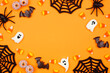 canvas print picture - Halloween frame of scattered candy and decor. Top down view over an orange background with copy space.
