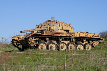 An old, rusty tank in a green meadow.