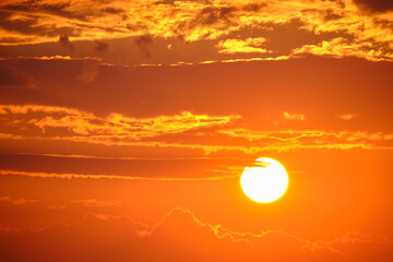 Wall Mural - Bright white setting sun against an orange sky at evening sunset.