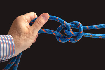 durable colored rope for climbing equipment on a dark background. knot of braided cable. item for tourism and travel