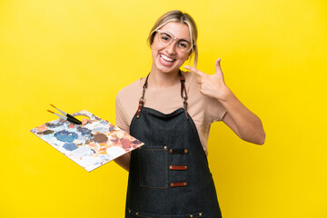 Wall Mural - Young artist caucasian woman holding a palette isolated  on yellow background giving a thumbs up gesture