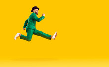 Happy Cheerful Young Man Wearing A Green Suit And A Black Hat Hurrying To A St Patrick's Day Party, Running Fast And Jumping High In The Air Isolated On A Bright Yellow Color Copy Space Background