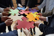 © Studio Romantic - Business team trying to find creative solutions to problem. Group of people connecting different red, yellow, orange, green, blue and purple jigsaw puzzle pieces. Cropped close up. Teamwork concept