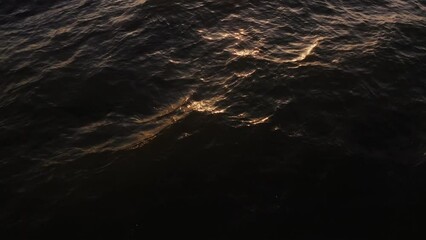 Wall Mural - Golden sunlight reflected in dark sea water, top view. Video from a drone, view of the sea waves, no land.