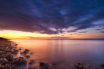 Wall Mural - A seaside sunset during sunset. A long exposure photo. Landscape during a bright sundown. The sea and reflections on the water.