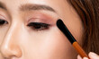 Closeup ardent young woman with healthy fair skin applying her eyeshadow with brush. Female model with fashion makeup. Beauty and makeup concept.
