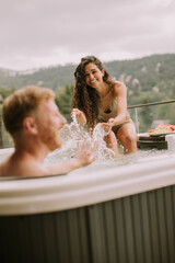 Young couple enjoying in outdoor hot tub on vacation