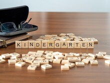 Kindergarten Wort Oder Konzept Dargestellt Durch Hölzerne Buchstabenfliesen Auf Einem Holztisch Mit Brille Und Einem Buch