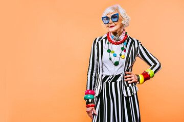 Cool and stylish senior old woman with fashionable clothes - Funny colorful portrait of elderly female lady on colored background