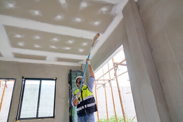 Wall Mural - Foreman painting on the ceiling of house construction site