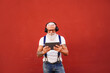 © neonshot - Happy senior man with white beard, mustache and tattoos listening to music with headphones and tablet. Concept of elderly people lifestyle, hobby, technology.