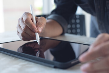 Wall Mural - Close up of man hand using stylus pen on digital tablet pc on table at home office