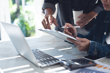 Canvas Print - Close up of two asian colleagues working together, have a discussion, using digital tablet and laptop computer at office with financial document on desk