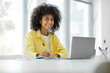 © Home-stock - Smiling young black woman looking at camera while sitting at table and working on laptop, free copy space