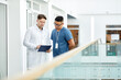 © Seventyfour - Waist up portrait of two doctors looking at clipboard while standing at balcony in modern clinic interior, copy space