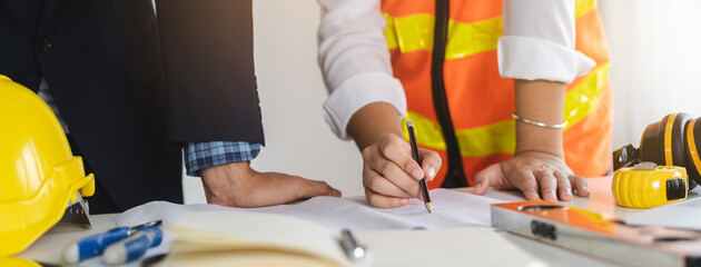 Close up hands of businessman from consultancy service discussing with project contractor and reviewing blueprint for build real estate facilities.