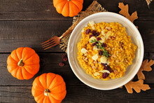 Fall Pumpkin Risotto With Cranberries And Parmesan Cheese. Overhead View Table Scene On A Rustic Wood Background.