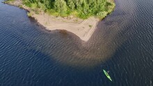 Slow Motion Fly Away Video On Women In Green Kayak Paddling From Small Island In Blue Lake In Scandinavian Mountains. Sweden, Norway