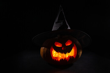 Wall Mural - Glowing pumpkin in a witch hat in the dark. Jack o lantern.