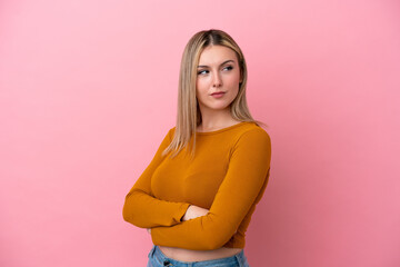 Wall Mural - Young caucasian woman isolated on pink background keeping the arms crossed