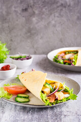 Wall Mural - Mexican tortilla wraps with  vegetables and chicken on a plate on the table. Vertical view