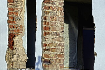 Sticker - ruins of an old building from a brown brick wall in white plaster on the street