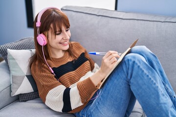 Poster - Young woman listening music writing on notebook at home