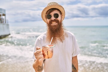 Sticker - Young redhead man smiling happy drinking cocktail at the beach.