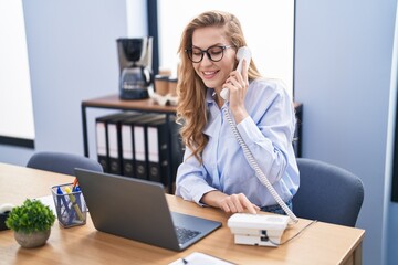 Poster - Young blonde woman business worker using laptop talking on the telephone at office