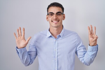 Canvas Print - Handsome hispanic man wearing business clothes and glasses showing and pointing up with fingers number eight while smiling confident and happy.