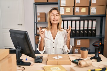 Canvas Print - Young blonde woman working at small business ecommerce gesturing finger crossed smiling with hope and eyes closed. luck and superstitious concept.