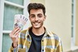 © Krakenimages.com - Handsome hispanic man smiling happy and confident at the city holding 1000 iceland krona banknotes